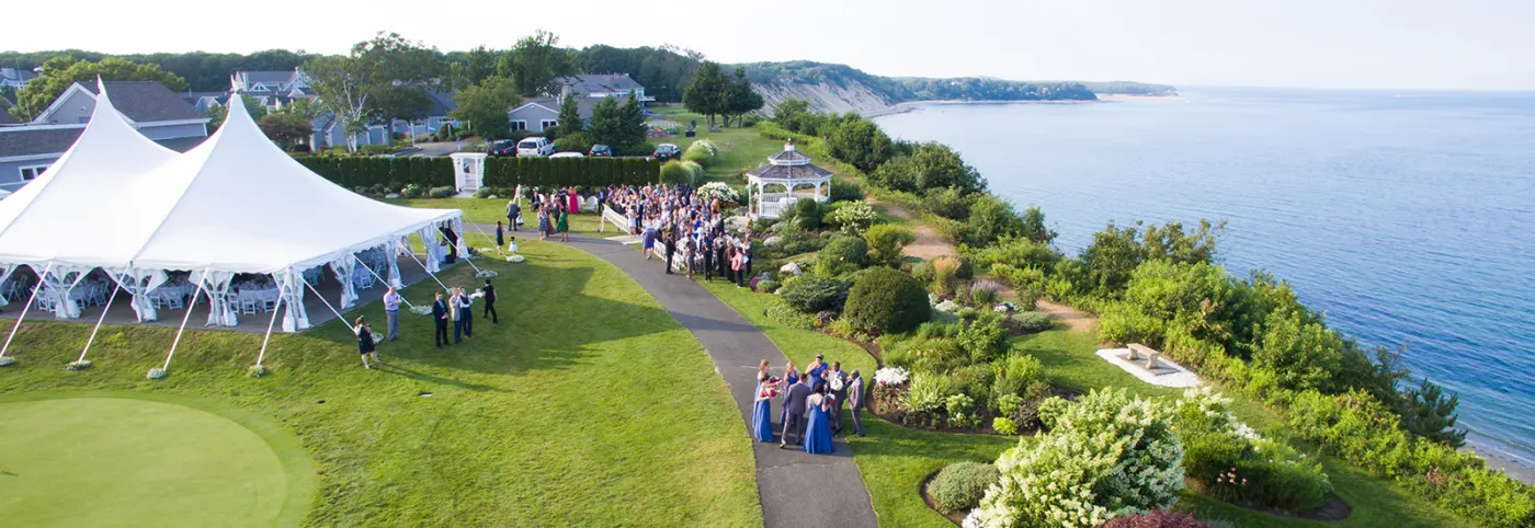 Wedding party gathered beside the tent with the bay beyond